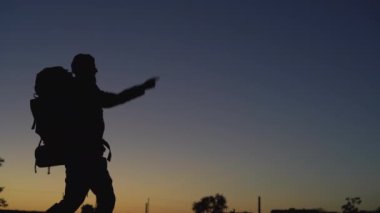 Büyük bir sırt çantası olan bir turistin silueti. Parmakla yazı yazmak için boş bir yere işaret ediyor..