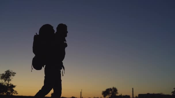 Silhouet van een toerist met een grote rugzak wijst met een vinger naar een lege ruimte voor tekst. — Stockvideo