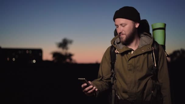 Portret męskiego turysty stojącego o zachodzie słońca wyciąga telefon i robi selfie — Wideo stockowe