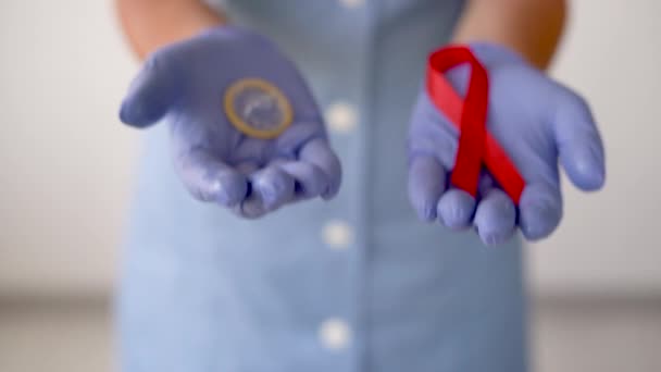 Zbliżenie żeńskich dłoni w rękawiczkach medycznych w jednej prezerwatywie w innej biurokracji. Dzień AIDS — Wideo stockowe