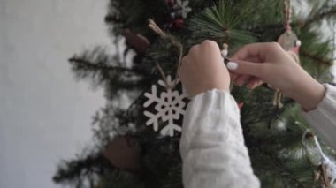 Kadın elinin yakın çekimi Noel ağacına bir melek oyuncağı asar.