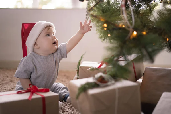 Noel Baba Şapkalı Küçük Bir Çocuk Bir Noel Ağacının Yanında — Stok fotoğraf