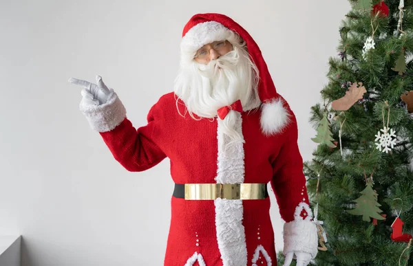 Der Weihnachtsmann Steht Neben Dem Weihnachtsbaum Und Zeigt Mit Dem — Stockfoto
