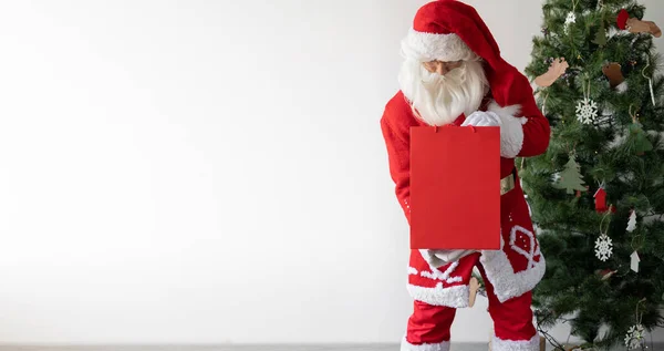 Der Weihnachtsmann Steht Neben Dem Weihnachtsbaum Hält Eine Große Papiertüte — Stockfoto