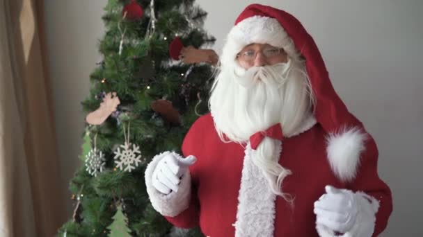 Papai Noel fica perto da árvore de natal levanta o polegar — Vídeo de Stock