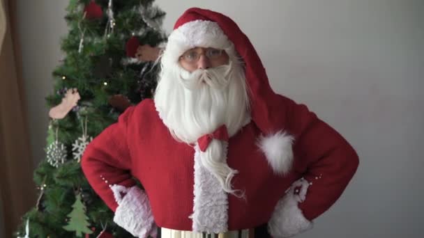 Babbo Natale si trova vicino all'albero di Natale guarda avanti ed è sorpreso. Si copre la bocca con la mano — Video Stock