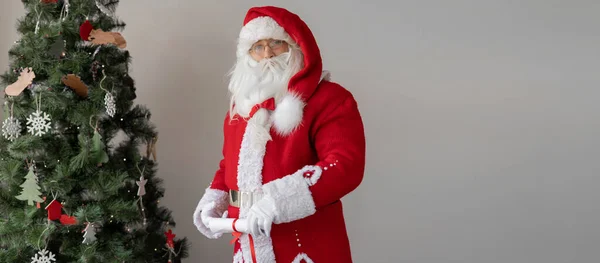 Święty Mikołaj Trzymający Zwinięty Papier Stojąc Przy Drzewie Wygląda Prosto — Zdjęcie stockowe