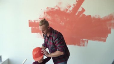 Adam çocuğu kollarına alır, duvarı boyamasına yardım eder. Ev yenileme konsepti