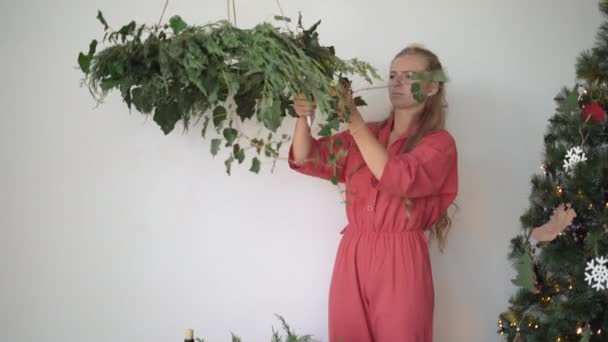 Florista mujer vestida con overoles hace una corona. Concepto de preparación navideña... — Vídeos de Stock