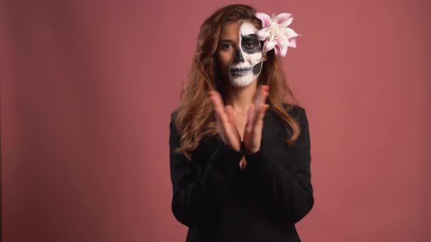 Portret van een vrouw in make-up voor Halloween. Schedel op het gezicht geschilderd. klapt handen — Stockvideo