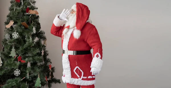 Święty Mikołaj Ubrany Czerwony Garnitur Stoi Blisko Choinki Przyłożył Rękę — Zdjęcie stockowe