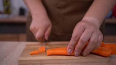 Kadın aşçı tahta üzerinde havuç kesiyor. Havuç diyeti salatasının profesyonel hazırlığı, yakın plan.