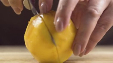 Olgun bir şeftaliyi kesen kadın ellerinin yakın çekimi. Makro video