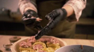 Mutfaktaki şef çiğ etten taze köfteleri yuvarlıyor ve pişirilmemiş makarnaların üzerine dikkatlice yerleştiriyor. İtalyan yemeği hazırlıyorum.