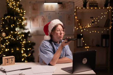 Hemşire ya da doktor bir hastaya sesli mesaj gönderiyor ve Noel arifesinde klinikte gece vardiyasında dizüstü bilgisayar kullanıyor. Sağlık ve Tıp Konsepti