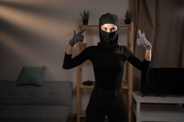 Kadın hırsız ya da kar maskeli soyguncu silah doğrultuyor. Hırsızlık, soygun ve hırsızlık konsepti