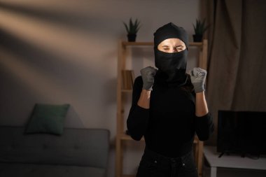 Siyah kar maskeli kadın soyguncu kazananı yumrukluyor. Hırsızlık, hırsızlık veya soygun konsepti