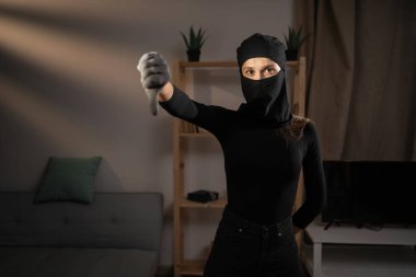 Mutsuz bir hırsız ya da siyah kar maskeli davetsiz bir misafir. Bir evin içinde, baş parmak göstererek hoş olmayan bir jesti işaret ediyor. Hırsızlık, suç, hırsızlık ve soygun kavramı. Boşluğu kopyala