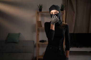 Kadın soyguncu ya da kar maskeli hırsız kötü kokan burnu parmaklarıyla sıkarken tiksinti ifadesiyle kameraya bakarken gösteriyor. Boşluğu kopyala