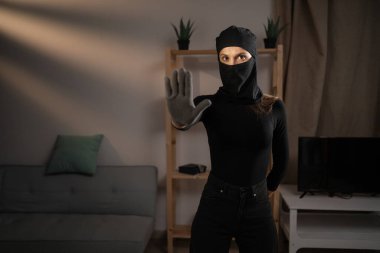 Kızgın kadın hırsız ya da kar maskeli soyguncu kameraya bakmayı reddeden avuç içi hareketlerini gösteriyor. Hırsızlık, suç, hırsızlık ve soygun kavramı.