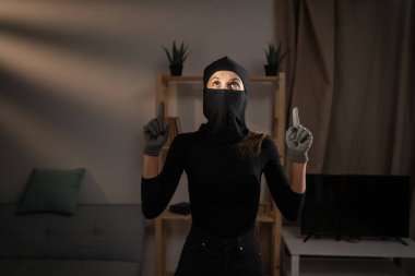 Bir evin içindeki kar maskeli hırsız ya da davetsiz misafir mesaj için uzayı işaret ediyor. Hırsızlık, suç, hırsızlık ve soygun kavramı. Boşluğu kopyala