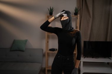 Kadın hırsız ya da siyah kar maskeli davetsiz misafir uzaktan bakar ve birini fark eder. Suç, soygun, hırsızlık ve hırsızlık kavramı