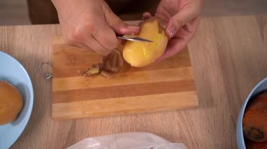 Kadınların elleri haşlanmış patatesi soyar, derisini bıçakla yüzer. Sebzeleri salata için hazırlama süreci. Üst Manzara. Yakın plan.