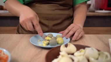 Haşlanmış tavuk yumurtası sarılarını karıştıran kadın tabakta bir çatalla ezilir. Yakın plan.