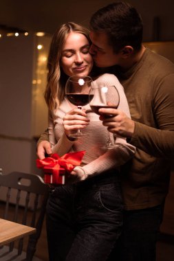 Sevgililer Günü 'nü kutluyoruz. Genç, tutkulu bir çift mutfakta kırmızı şarap içiyor ve geceyi birlikte geçiriyorlar. Boşluğu kopyala