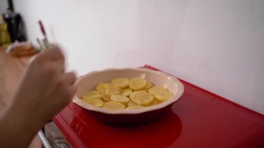 Kadın fırında pişirmeden önce patates hazırlıyor fırına baharat döküyor. Boşluğu kopyala