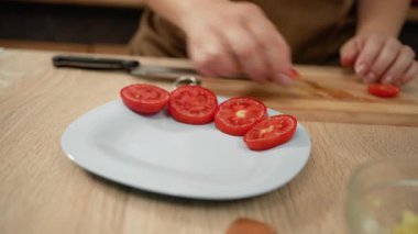 Caprese salatası pişiren kadına yakın çekim. Şef kırmızı domates kesiyor.