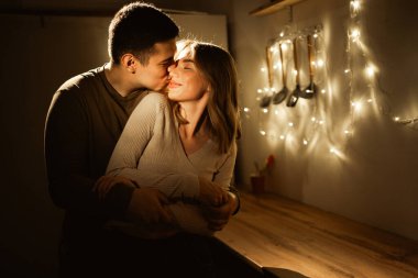 Aşk ve bağlılık kavramı. Geceleri mutfakta sarılan bir çift. Romantizm tatlı bir anı kucaklıyor. Boşluğu kopyala