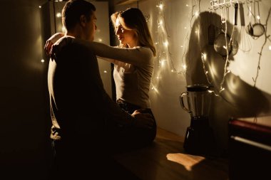 Geceleri mutfakta tutkulu, çekici bir çift. Adam, bir kadına masa başında otururken sarılıyor. Boşluğu kopyala