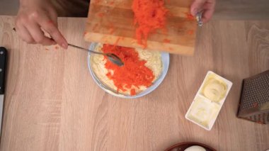 Haşlanmış sebze ve mayonez ile geleneksel katmanlı salata pişirme işlemi. Şef kürk tabağının altında ringa balığı hazırlarken rendelenmiş havucu mayonez tabakasına ekler. en üstteki görünüm