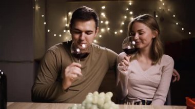 Genç ve güzel bir çift, doğum gününü ya da evde randevusunu kutlamak için kadeh kaldırıyor. Sevgililer Günü 'nü kutlamak için ellerinde şarap kadehleri olan sevgili. Boşluğu kopyala