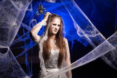 Korkunç cadılar bayramı zombi makyajlı şaşkın, şaşkın, şaşkın kadın kaşınıyor. Mavi örümcek ağında yara izi olan ölü bir kız. Boşluğu kopyala