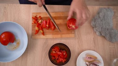 Cutting tomatoes for making eggs with salo and vegetables for breakfast at home. close-up. Top view