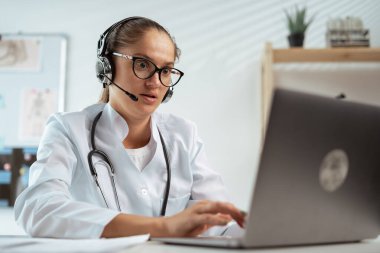 Dizüstü bilgisayar kullanan kulaklıklı kadın doktor. teletıp kavramı