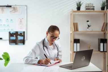 Doktor kadın dizüstü bilgisayarla tıbbi kayıtlar yazıyor. Tıp ve Sağlık Hizmetleri kavramı