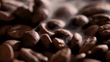 extreme macro closeup of roasted coffee beans surrounded by rising smoke creating strong aroma atmosphere. concept of coffee brewing