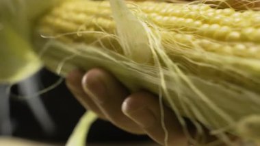 Erkek ellerinin yakın çekimi mısır kabuklarını soyar. Vejetaryen yemeği. Boşluğu kopyala