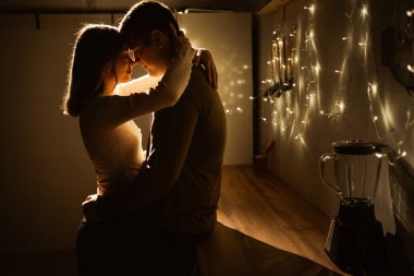 Romantic evening. Couple of lovers silhouette against background of garlands with lights. Copy space