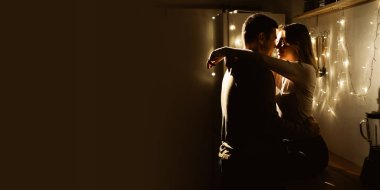 Passionate romantic couple hugging and kissing at night on the kitchen. Banner. Copy space