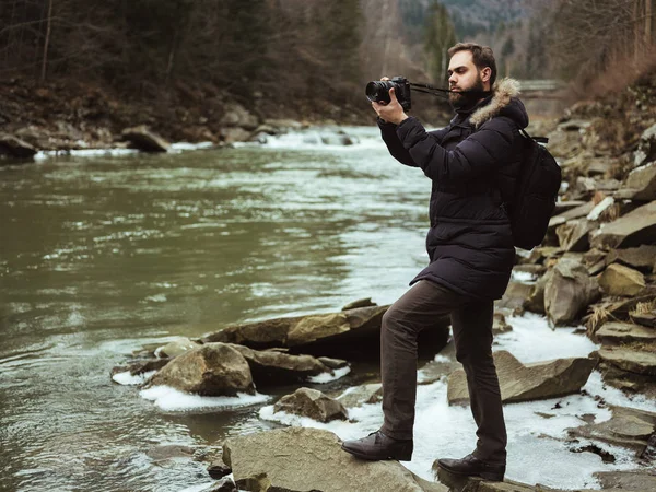 Человек путешественник фотограф с камерой фотографируя реку — стоковое фото