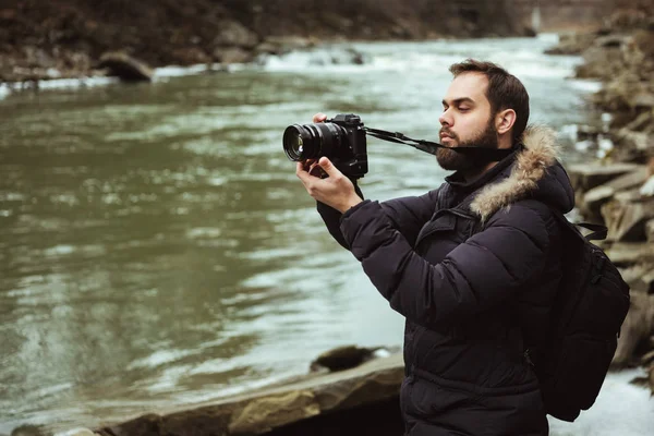 Man traveler photographer with camera photographing the river