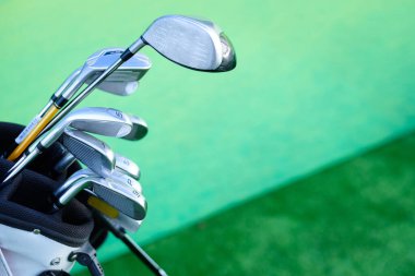 Yeşil arka planda golf sopalarının yakın plan çekimi.