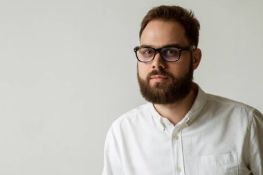 Güzel sakallı yakışıklı bir adamın portresi. Beyaz arka planda, fotokopi alanı ile izole edilmiş. Siyah çerçeveli beyaz gömlek ve gözlük giyen bir manken.