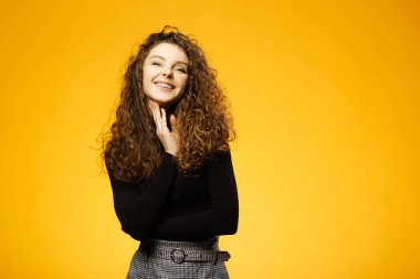 Pretty girl with curly hair isolated on yellow background clipart