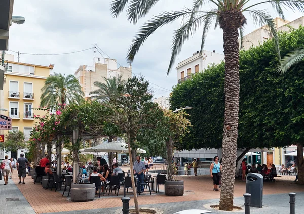 アリカンテ スペイン 2018 の人々 観光客や行楽客夏季アリカンテ市内中心部の通りの歩道のカフェで座っています 熱帯の咲く茂みの正方形およびヤシの木 スペイン — ストック写真
