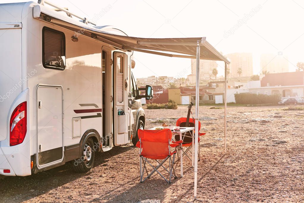 Empty folding chairs and table under canopy near recreational vehicle camper trailer. Adventure, active people traveling by motor home concept